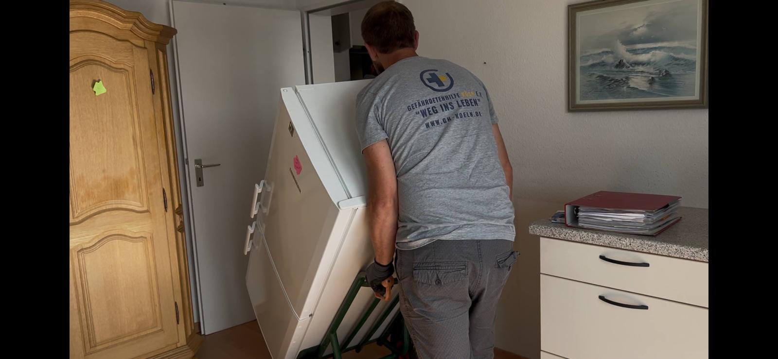 Mitarbeiter mit Rümpelretter-Shirt, Rückseite zeigt 'Gefährdetenhilfe Köln e.V. · Weg ins Leben'