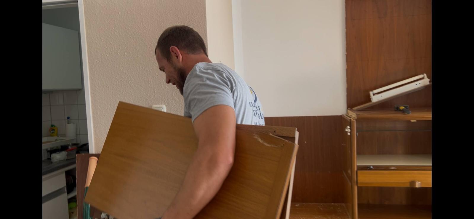 Mitarbeiter packt Porzellan sorgsam in eine Transport-Wanne, im Hintergrund vorbereitete Gepäckstücke